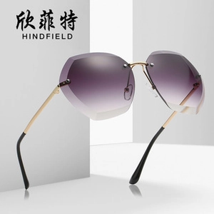 Detail of oversized rimless sunglasses featuring gradient purple lenses and golden metal temples