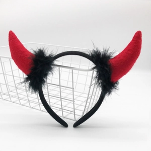 Detail of red devil horns headband with black feathers on white background