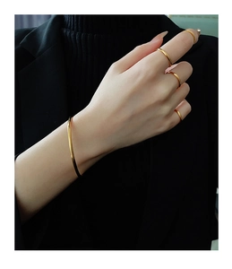 Polished gold bangles and rings styled on black knitwear for a sophisticated look