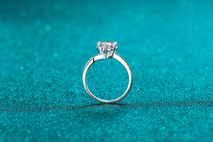 Macro view of six-prong moissanite engagement ring on shimmering blue background