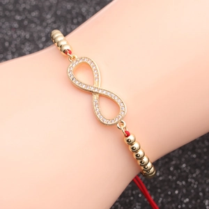 Detailed view of infinity charm with white zircons on red woven rope bracelet