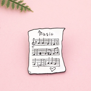 Détail de la broche en émail partition de musique sur un fond rose esthétique