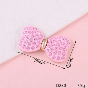 Pink rhinestone bow jewelry piece with enamel finish and gold edges, 33mm x 18mm size