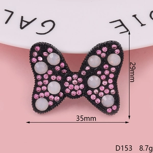 Macro shot of 35x29mm black bow accessory with pink rhinestones and white pearls