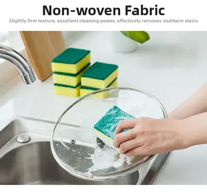 Dual-layer cleaning sponge with green scouring pad scrubbing a metal pot lid