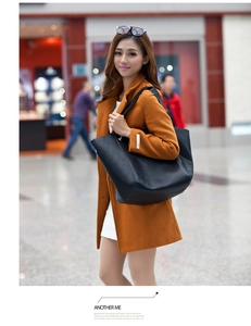 Detailed view of black leather tote bag worn with a caramel coat in a street setting