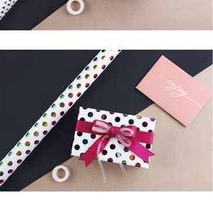 Detail of white wrapping paper with metallic colorful polka dots and ribbon bow decoration
