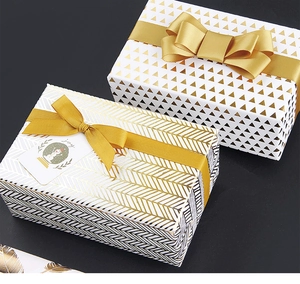 Close-up of gift boxes with gold geometric patterns, satin ribbons, and joy gift tags