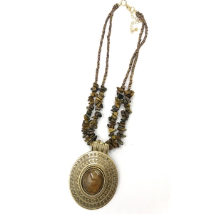 Detail of vintage bronze pendant with oval tiger eye stone and spiral floral carvings