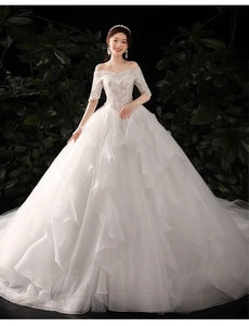 Detail view of lace embroidery and shimmering sequins on the white off-shoulder bridal gown