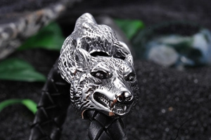 Detailed macro view of intricately cast double wolf heads on a braided leather bracelet