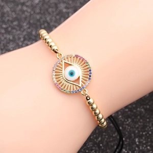 Gold evil eye bead bracelet with colorful zircon inlay on dark textured background