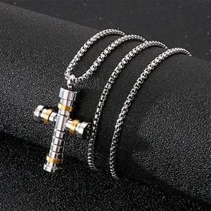 Collier croix en argent pour homme avec anneaux dorés sur une surface noire texturée