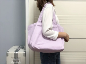 Gedetailleerd zijaanzicht van een grote lavendel canvas draagtas gedragen door een model