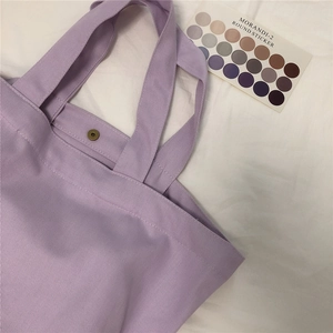 Detailweergave van een lavendelkleurige canvas tas met magneetknoopsluiting en de stoftextuur