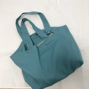 Detail van een teal canvas draagtas met een vintage bronzen metalen drukknoopsluiting