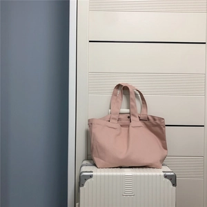 Roze canvas draagtas getoond vanuit een hoek van 45 graden op een witte koffer