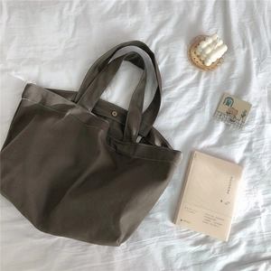 Detail van canvas tote bag met metalen drukknoopsluiting op witte stoffen achtergrond