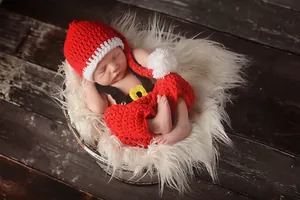 Macro detail of handmade crochet baby Christmas outfit with red hat and shorts