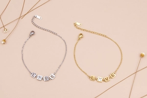 Dettaglio delle perline quadrate incise LOVE sui braccialetti in acciaio oro e argento