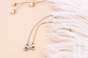 Dettaglio delle chiusure a moschettone oro e argento su catenine con decori floreali