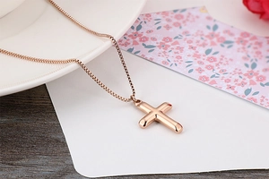Close-up of a rose gold minimalist cross pendant necklace on a decorative floral card