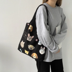 Close-up of black canvas tote bag with colorful cartoon dog illustrations and casual styling