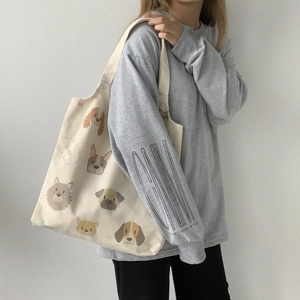 Detail shot of a beige canvas tote bag with artistic cartoon dog illustrations