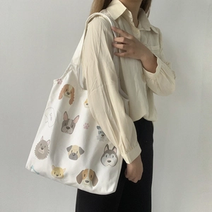 Close-up of white canvas tote bag featuring cute cartoon dog illustrations and durable straps