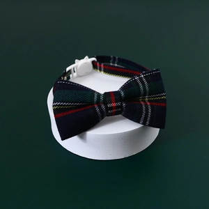 Detail of green plaid pet collar with a bow tie and white buckle on round display base