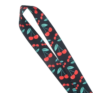 Close-up of fabric lanyard with red cherry pattern and green leaves on black background