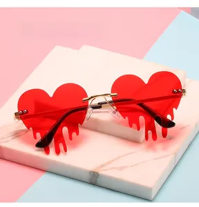 Dettaglio degli occhiali da sole rossi a cuore senza montatura con effetto goccia e oro