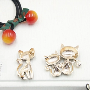 Detailed back view of gold cat brooches showing secure pin fastener and metal texture