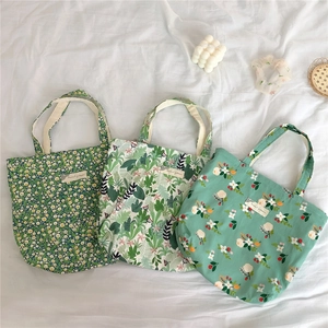 Flat lay of small floral cotton handbags with tropical leaf patterns and cute cloth labels