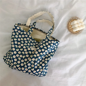 Close-up of blue floral cotton tote bag with white flower prints and cream canvas handles