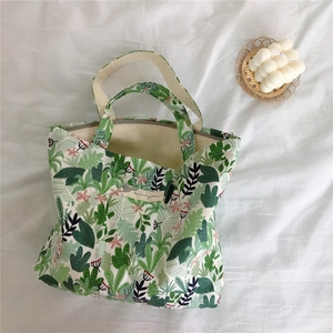 Detail of floral canvas tote bag featuring green leaf pattern and cotton handles