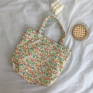 Close-up of floral cotton tote bag with red flowers and beige label on white fabric