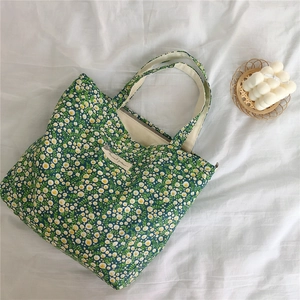 Detail of green floral cotton tote bag with white yellow flowers and fabric label