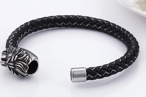 Detail of black braided leather bracelet with silver stainless steel lion head clasp