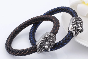 Detail of woven leather bracelets featuring silver lion head charm on white background