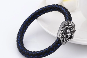 Detail of woven leather bracelet with silver lion head clasp and blue stitching