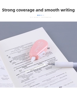 Detailed view of pink macaron correction tape and white gel pen on an open book