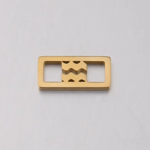 Close-up of golden rectangular Aquarius zodiac charm with hollowed metal engraving