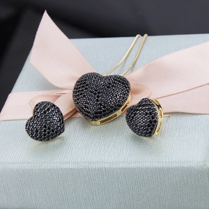 Macro shot of heart jewelry set with black zircon in a light blue gift box with pink ribbon