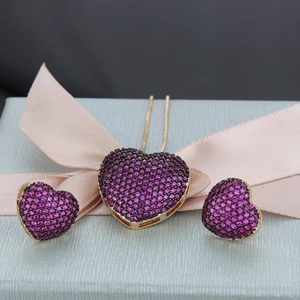Macro shot of gold plated heart jewelry set with pink stones on a light blue gift box
