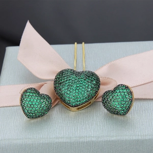 Detail view of heart-shaped jewelry set with green cubic zirconia in a blue gift box