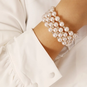 Detailed close-up of multi-layer pearl bracelet with golden rhinestones on a wrist