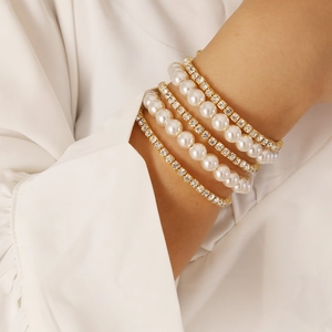 Close-up of multilayer gold bracelet set with white pearls and sparkling rhinestones