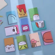 Flat lay of colorful mini cartoon notebooks with diverse cute face illustrations