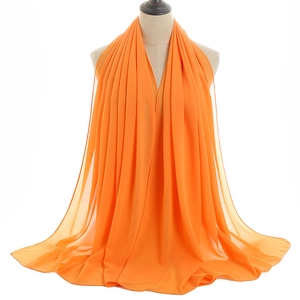 Detail of vibrant orange chiffon hijab with a smooth drape and semi-transparent texture
